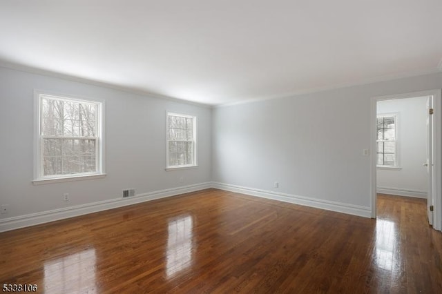 empty room featuring crown molding, plenty of natural light, and hardwood / wood-style floors