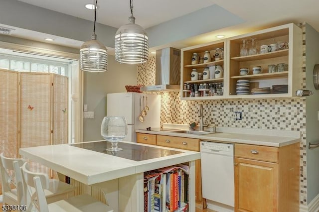 kitchen featuring wall chimney range hood, white appliances, sink, a breakfast bar, and decorative backsplash