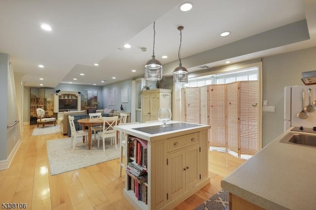 kitchen with pendant lighting, sink, white refrigerator, light hardwood / wood-style floors, and a kitchen island