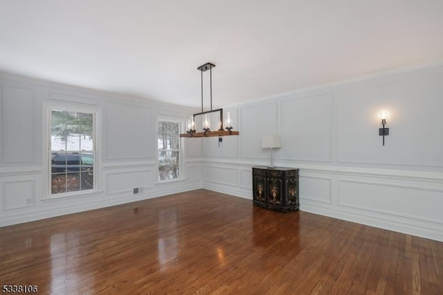 unfurnished dining area with ornamental molding, dark hardwood / wood-style floors, and a chandelier