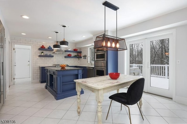 kitchen featuring light tile patterned floors, blue cabinetry, appliances with stainless steel finishes, hanging light fixtures, and tasteful backsplash