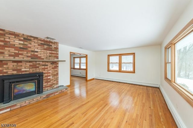 unfurnished living room featuring baseboard heating, a brick fireplace, and light hardwood / wood-style flooring