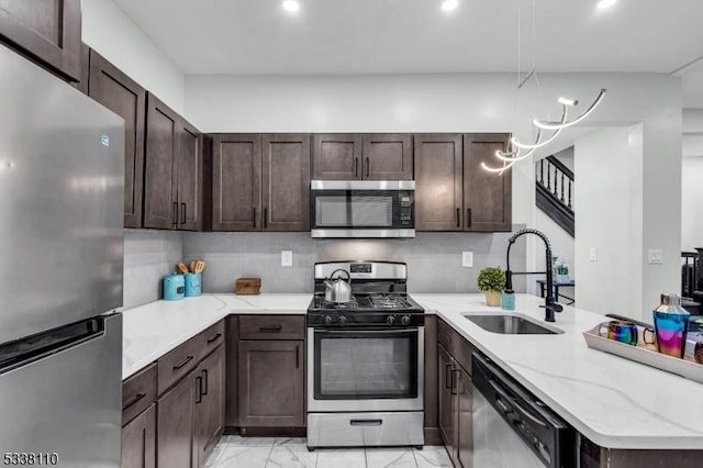 kitchen featuring appliances with stainless steel finishes, sink, light stone counters, kitchen peninsula, and dark brown cabinets