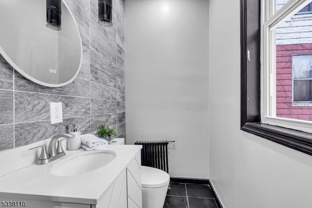 bathroom with radiator, tile patterned flooring, tile walls, vanity, and toilet