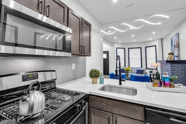 kitchen with dark brown cabinetry, sink, gas range, and dishwasher