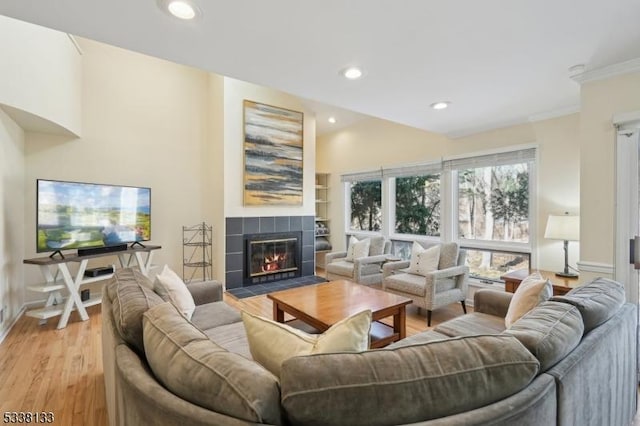 living room with lofted ceiling, light hardwood / wood-style floors, and a tiled fireplace