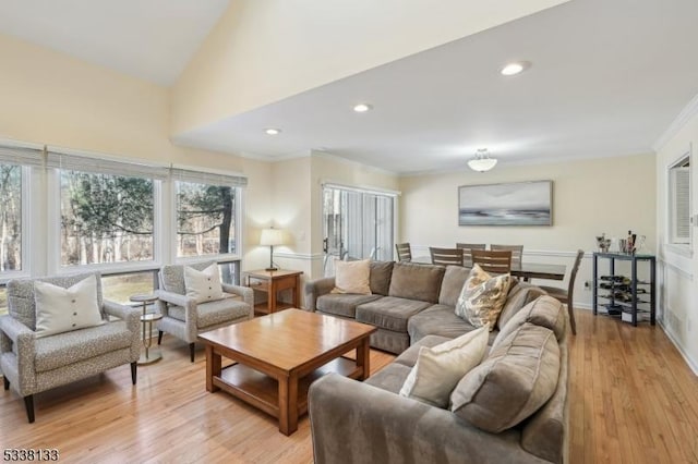 living room with ornamental molding, light hardwood / wood-style flooring, and lofted ceiling