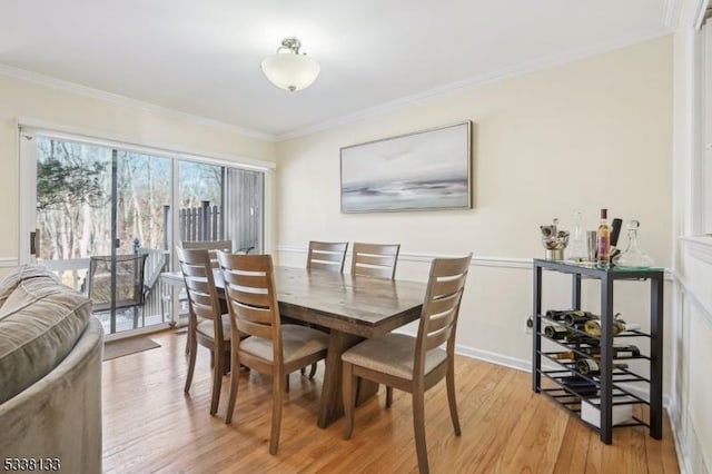 dining area with light wood-type flooring and ornamental molding