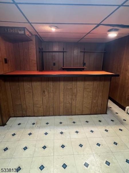 bar featuring a paneled ceiling and wood walls