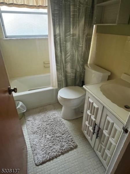 full bathroom featuring toilet, vanity, and shower / bathtub combination with curtain