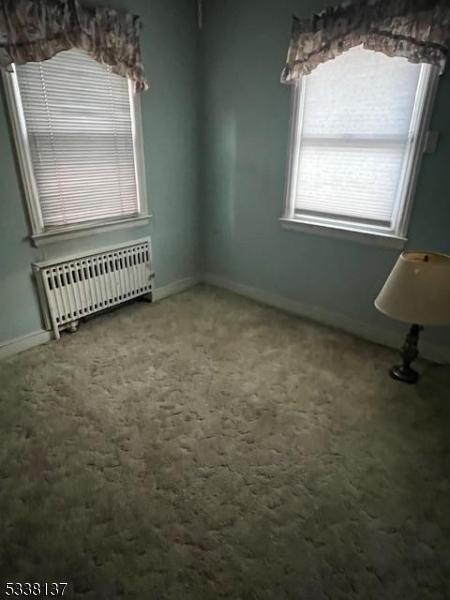 unfurnished dining area featuring carpet floors and radiator heating unit