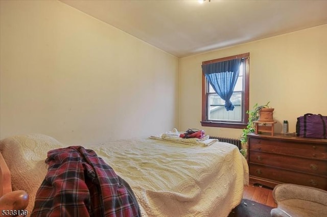 bedroom with radiator heating unit and wood-type flooring