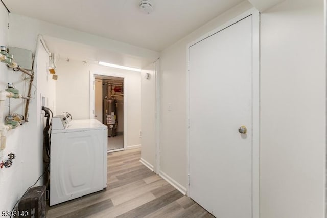 clothes washing area with washer / clothes dryer, water heater, and light hardwood / wood-style floors