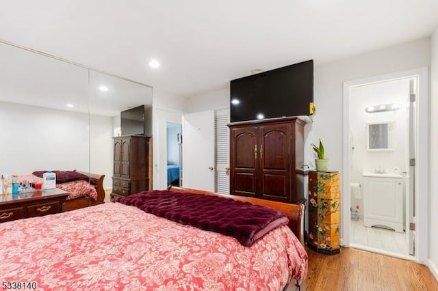 bedroom with ensuite bathroom and hardwood / wood-style flooring