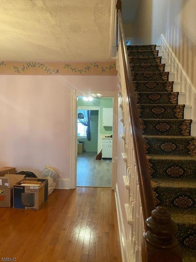 staircase featuring hardwood / wood-style flooring and a textured ceiling