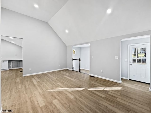 unfurnished living room with vaulted ceiling and light wood-type flooring