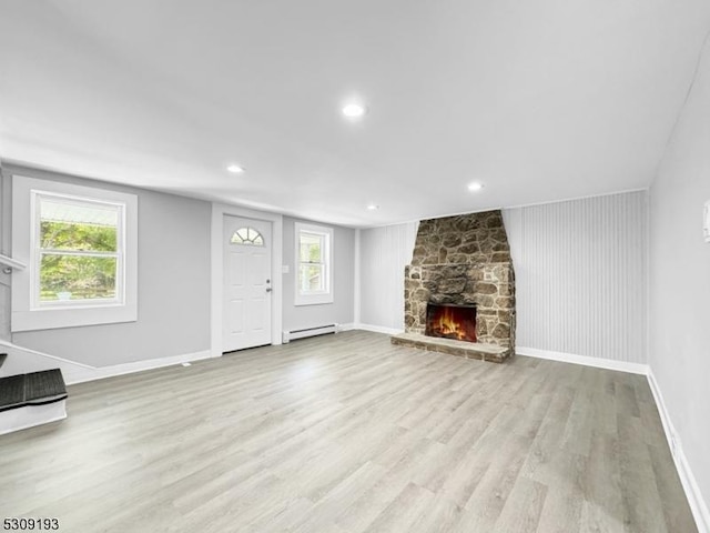 unfurnished living room with light hardwood / wood-style flooring, a baseboard radiator, and a healthy amount of sunlight