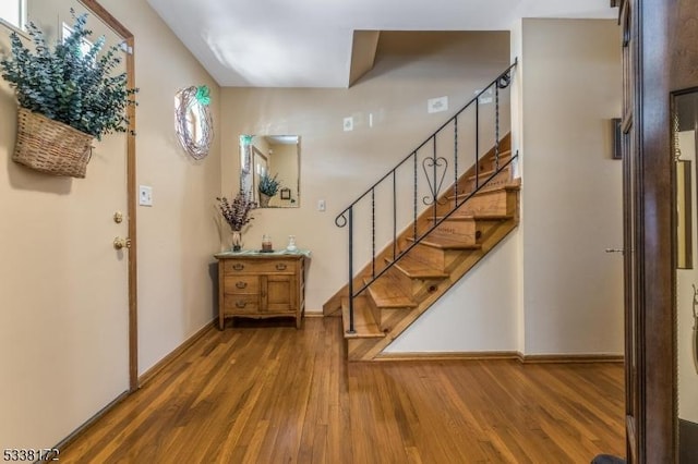 entryway with stairs, wood finished floors, and baseboards