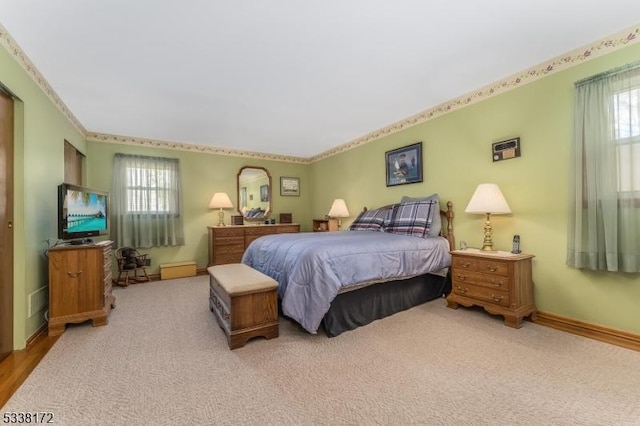 bedroom featuring light carpet, multiple windows, and baseboards