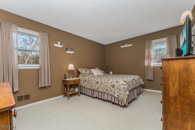 bedroom with baseboards, visible vents, and light colored carpet