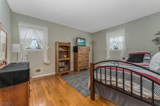 bedroom with visible vents, baseboards, and wood finished floors