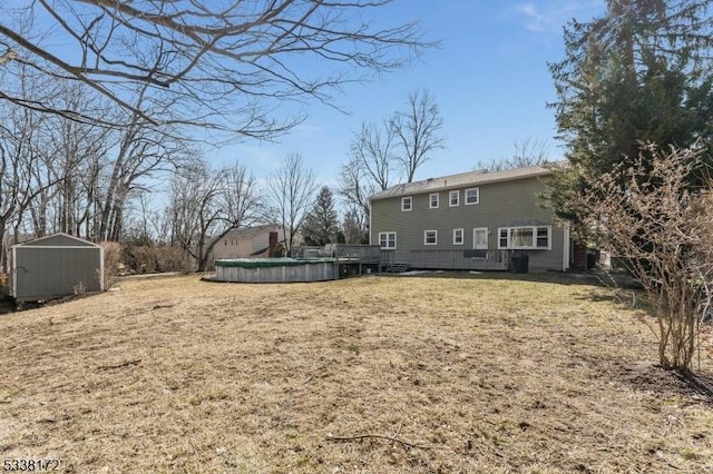 view of yard featuring a covered pool, a shed, a deck, and an outbuilding