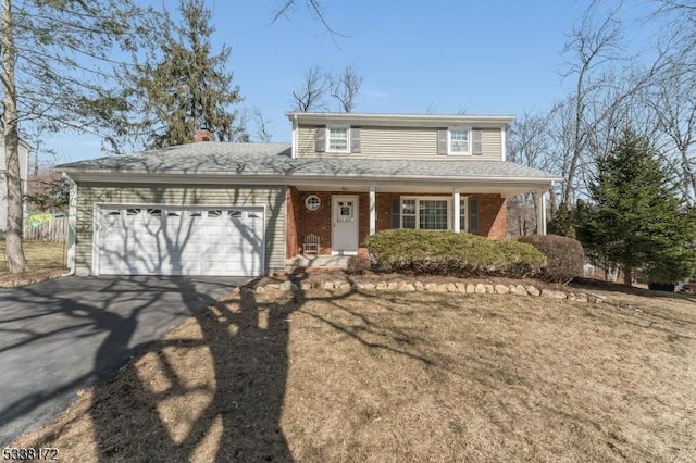 traditional-style house featuring an attached garage, aphalt driveway, and brick siding