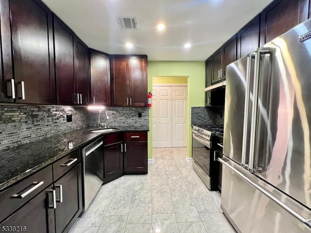 kitchen with stainless steel appliances, tasteful backsplash, sink, and dark stone countertops