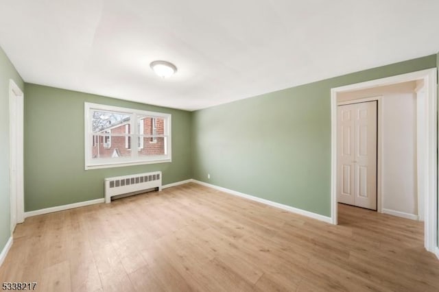 unfurnished bedroom with radiator and light wood-type flooring