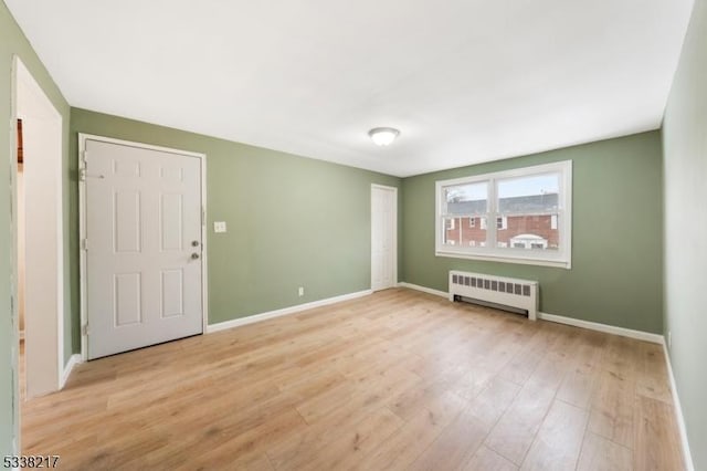 unfurnished room with radiator heating unit and light hardwood / wood-style flooring