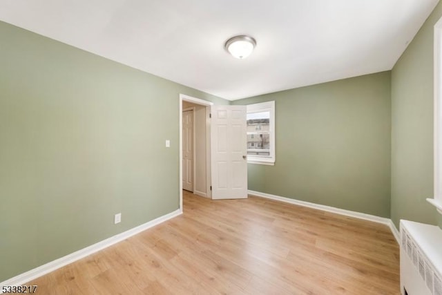unfurnished room with radiator and light hardwood / wood-style flooring