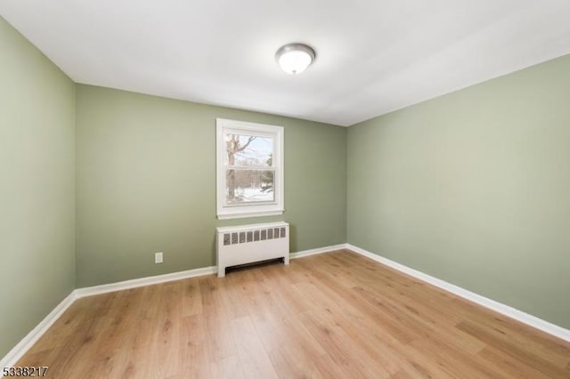 unfurnished room featuring radiator and light wood-type flooring