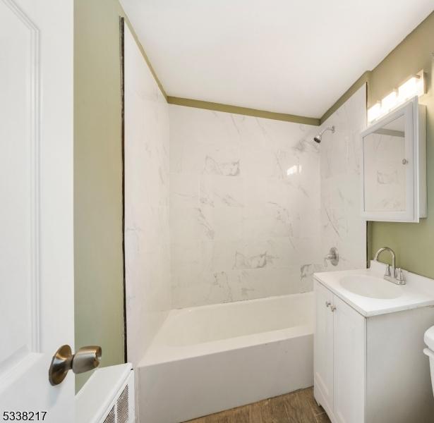 full bathroom with vanity, hardwood / wood-style flooring, toilet, and tiled shower / bath