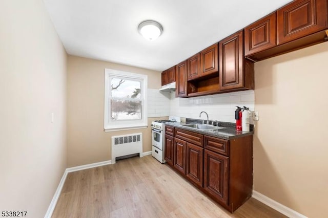 kitchen featuring sink, light wood-type flooring, radiator heating unit, white gas range oven, and backsplash