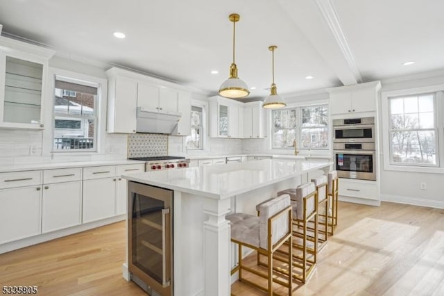 kitchen featuring a breakfast bar, double oven, wine cooler, white cabinets, and a kitchen island