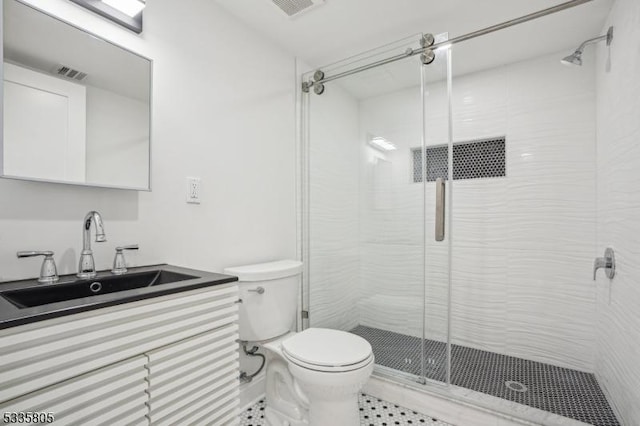 bathroom featuring vanity, a shower with door, and toilet