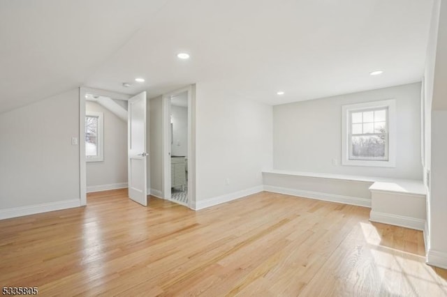 bonus room with lofted ceiling, plenty of natural light, and light wood-type flooring