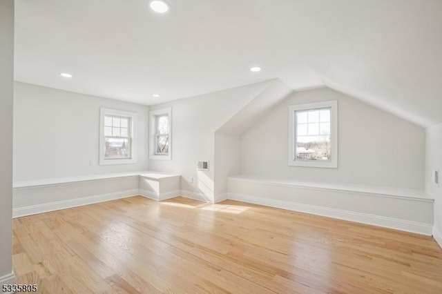 additional living space featuring vaulted ceiling and light hardwood / wood-style floors