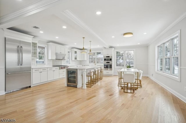 kitchen with appliances with stainless steel finishes, a breakfast bar, decorative light fixtures, white cabinets, and a center island