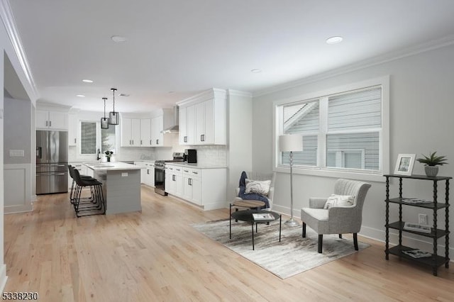 kitchen with a kitchen island, pendant lighting, white cabinets, stainless steel appliances, and crown molding