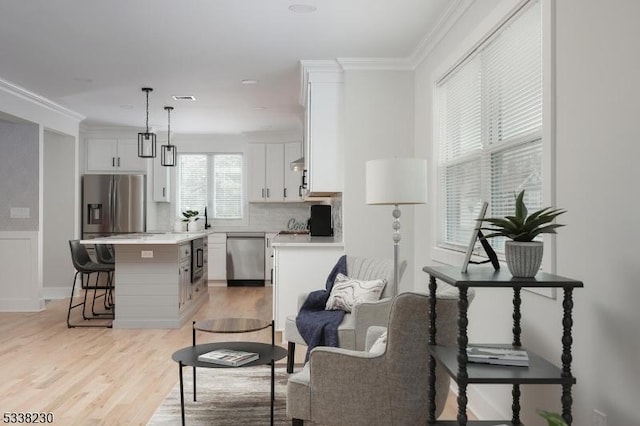 kitchen with decorative light fixtures, light hardwood / wood-style flooring, a kitchen island, stainless steel appliances, and white cabinets