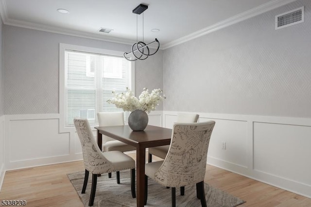 dining space featuring an inviting chandelier, crown molding, and light wood-type flooring