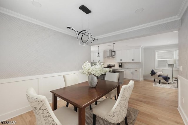 dining space with ornamental molding, a chandelier, and light hardwood / wood-style floors