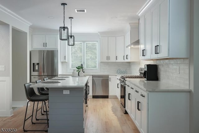 kitchen featuring white cabinetry, crown molding, a kitchen island, and appliances with stainless steel finishes