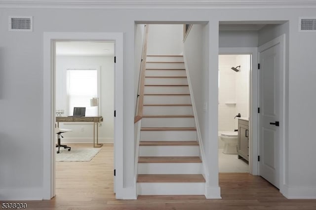 stairs featuring crown molding and hardwood / wood-style floors