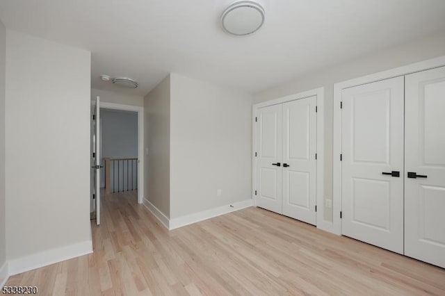 unfurnished bedroom with two closets and light hardwood / wood-style floors