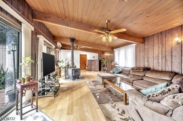 living room with a wood stove, wooden ceiling, beam ceiling, and light hardwood / wood-style flooring