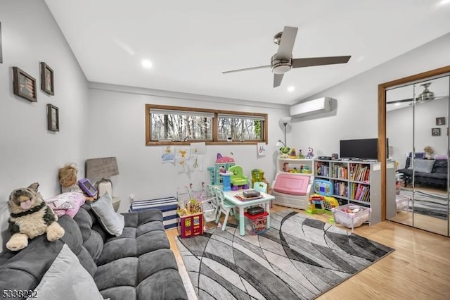 recreation room with hardwood / wood-style flooring, a wall mounted AC, and ceiling fan