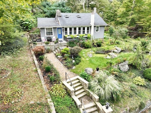 back of house featuring stairs, a chimney, and roof with shingles