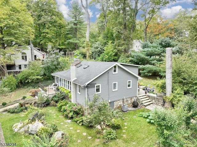 exterior space with a shingled roof, stairway, and a chimney